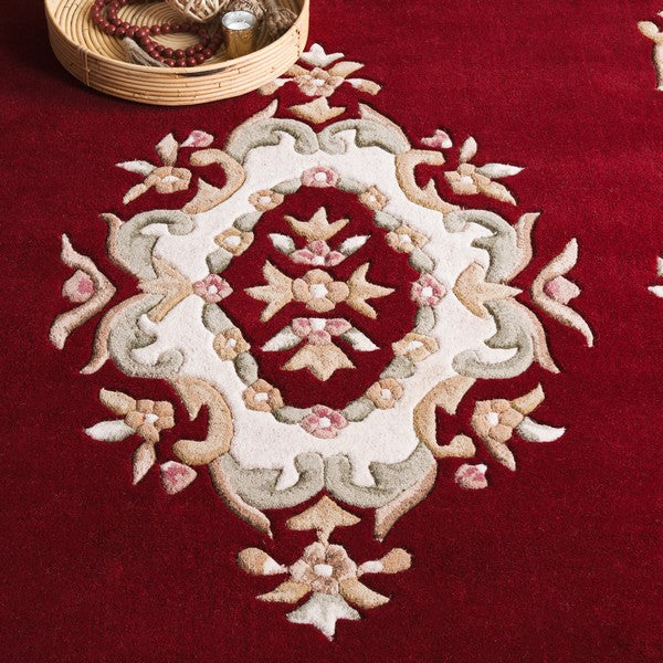 Detailed view of Aurelia dark red wool rug showing hand tufted floral medallion texture